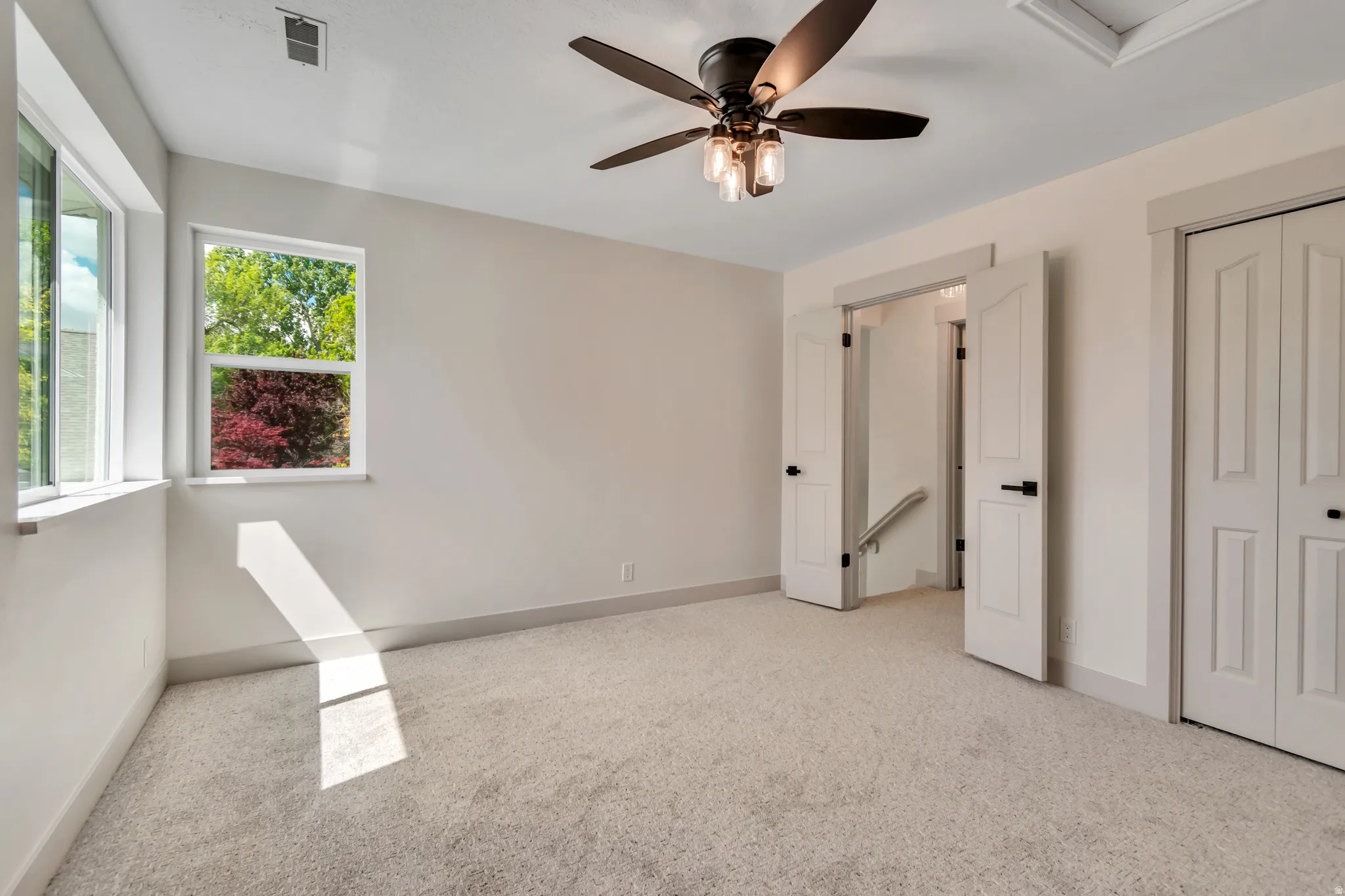 Unfurnished bedroom with light colored carpet, ceiling fan, and a closet