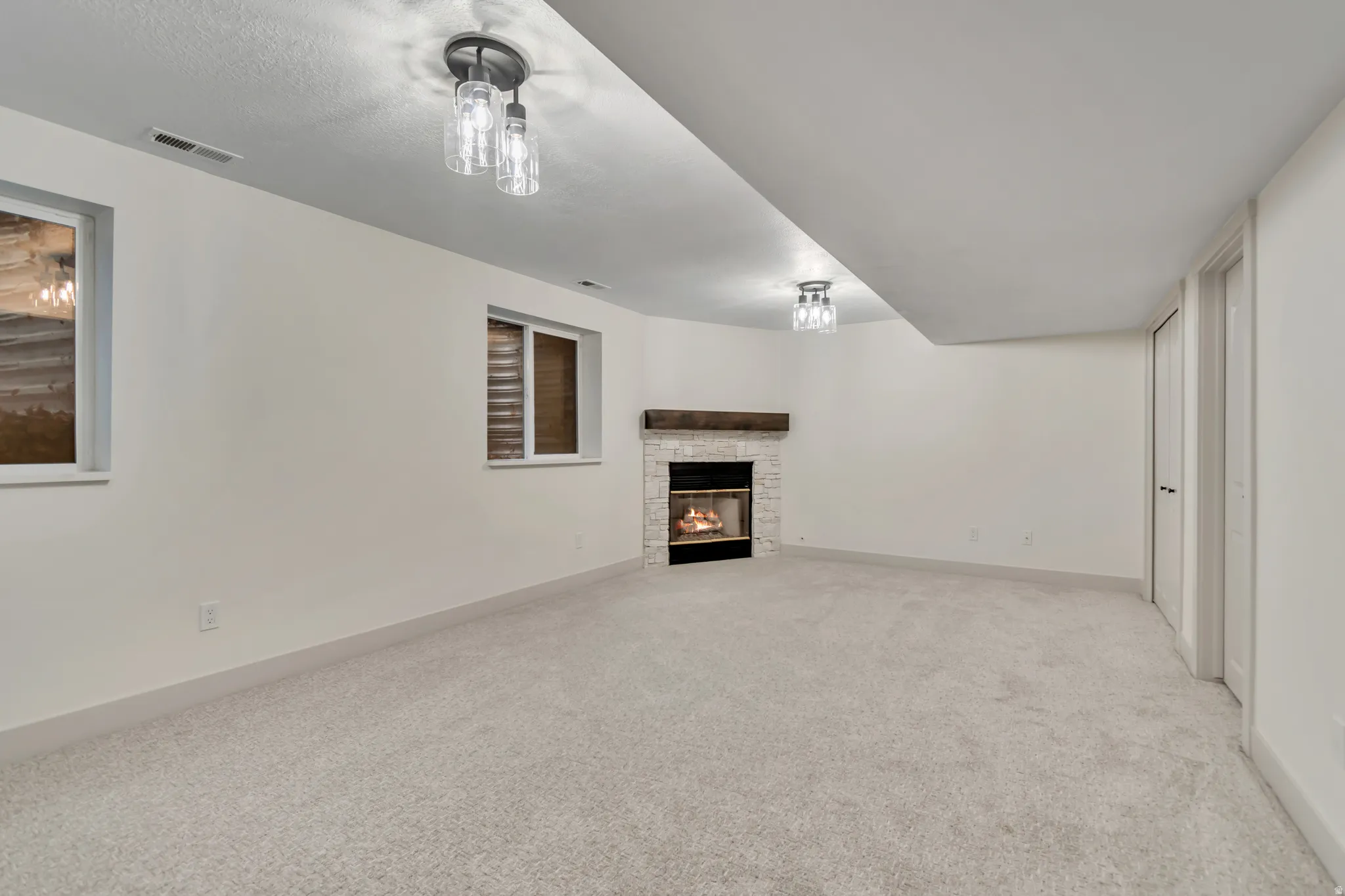 Unfurnished living room with light colored carpet and a fireplace