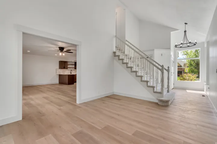 Stairway featuring a high ceiling, hanging lights, wood finished floors, and ceiling fan