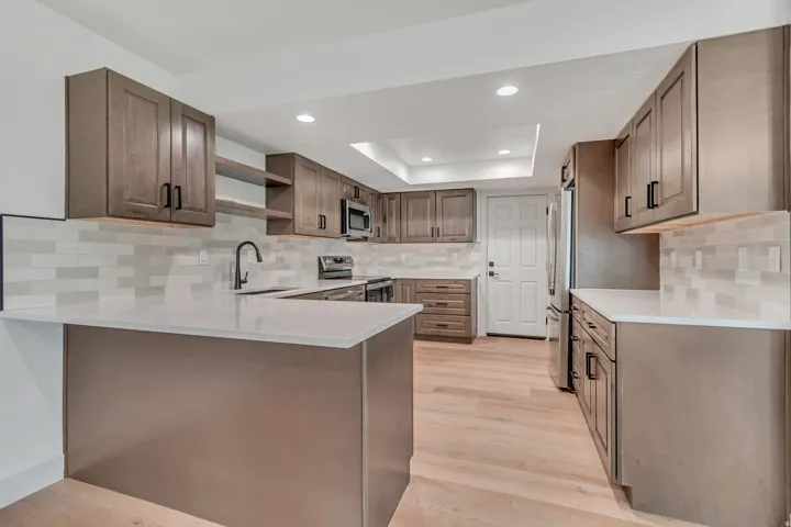 Kitchen with a peninsula, recessed lighting, open shelves, stainless steel appliances, and light wood-style floors