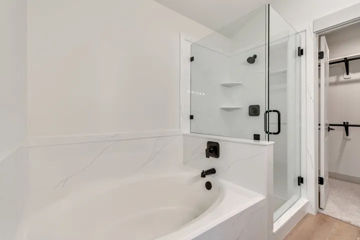 Full bathroom with a walk in closet, a marble finish shower, a garden tub, and light wood finished floors