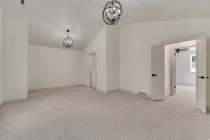Bonus room featuring light colored carpet, hanging lights, and vaulted ceiling