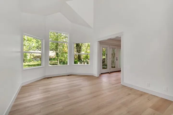 Unfurnished room featuring french doors, light wood finished floors, and lofted ceiling