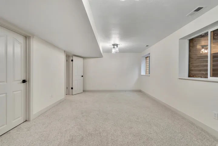 Unfurnished room featuring light carpet and baseboards