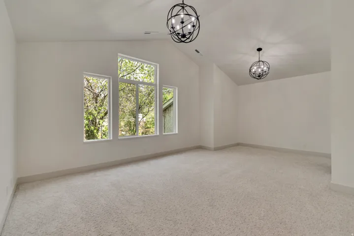 Empty room with suspended lighting and light carpet