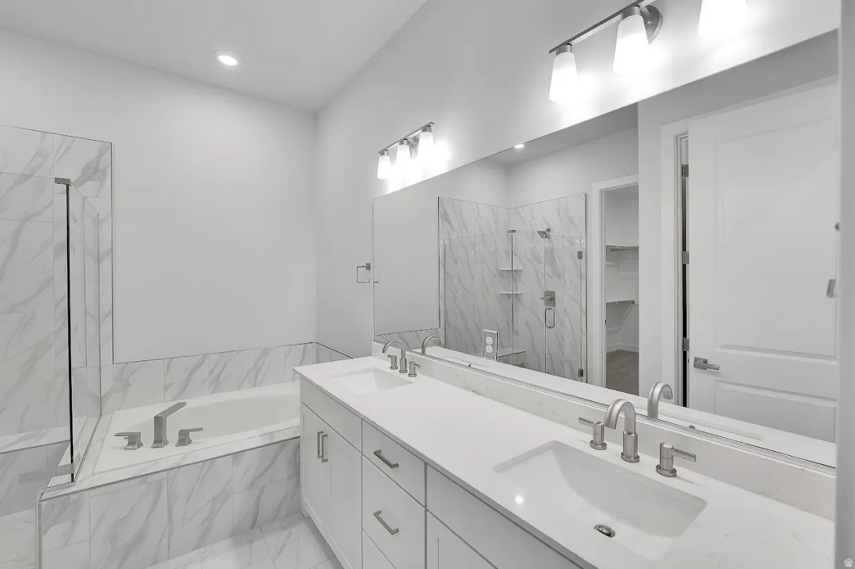 Bathroom with a marble finish shower, double vanity, a garden tub, light marble finish flooring, and a walk in closet
