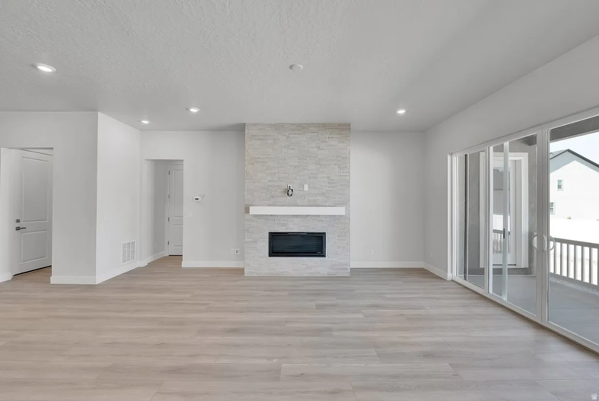 Unfurnished living room with light wood-type flooring, recessed lighting, a fireplace, and a textured ceiling