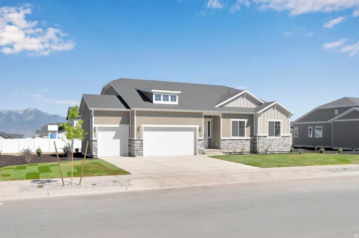 Craftsman-style home featuring board and batten siding, an attached garage, stone siding, and a front lawn