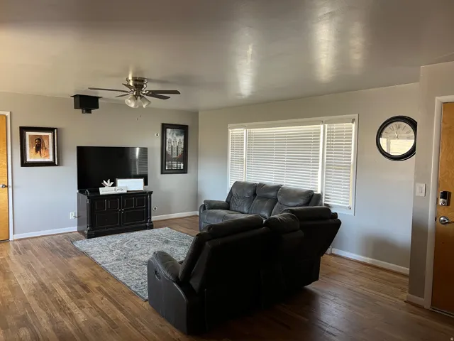 Living room with a ceiling fan and hardwood / wood-style flooring