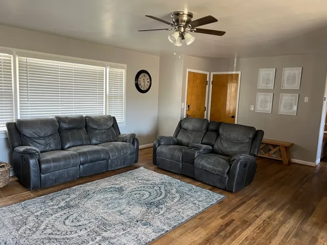 Living room featuring a ceiling fan and dark wood-type flooring
