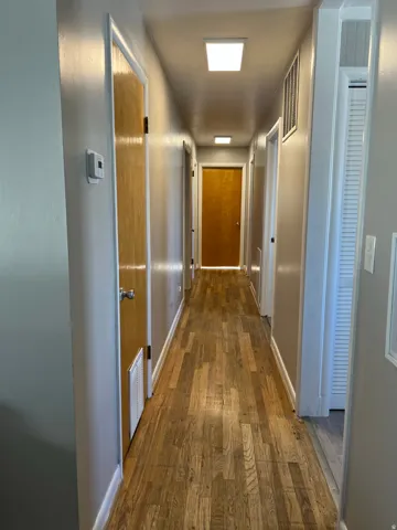 Corridor with dark wood-style flooring and baseboards