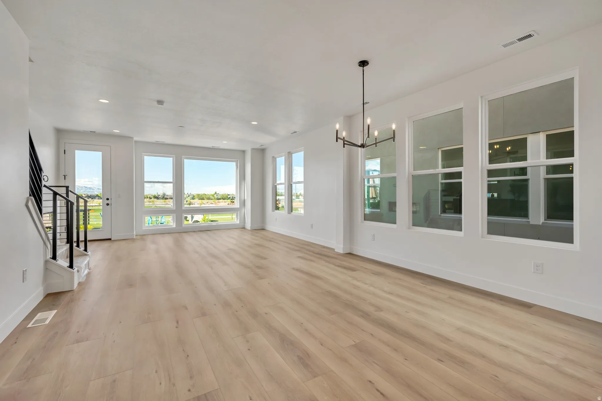 Unfurnished living room with a chandelier and light wood-type flooring