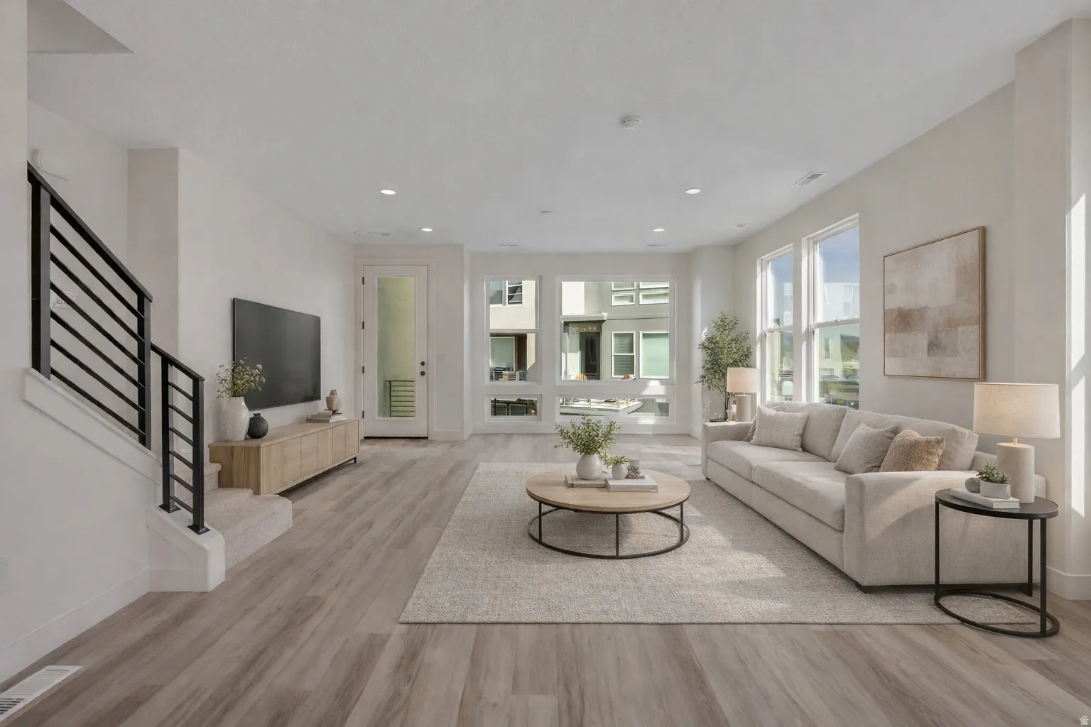 Spacious living area featuring wood-finish flooring, recessed lighting, and large windows