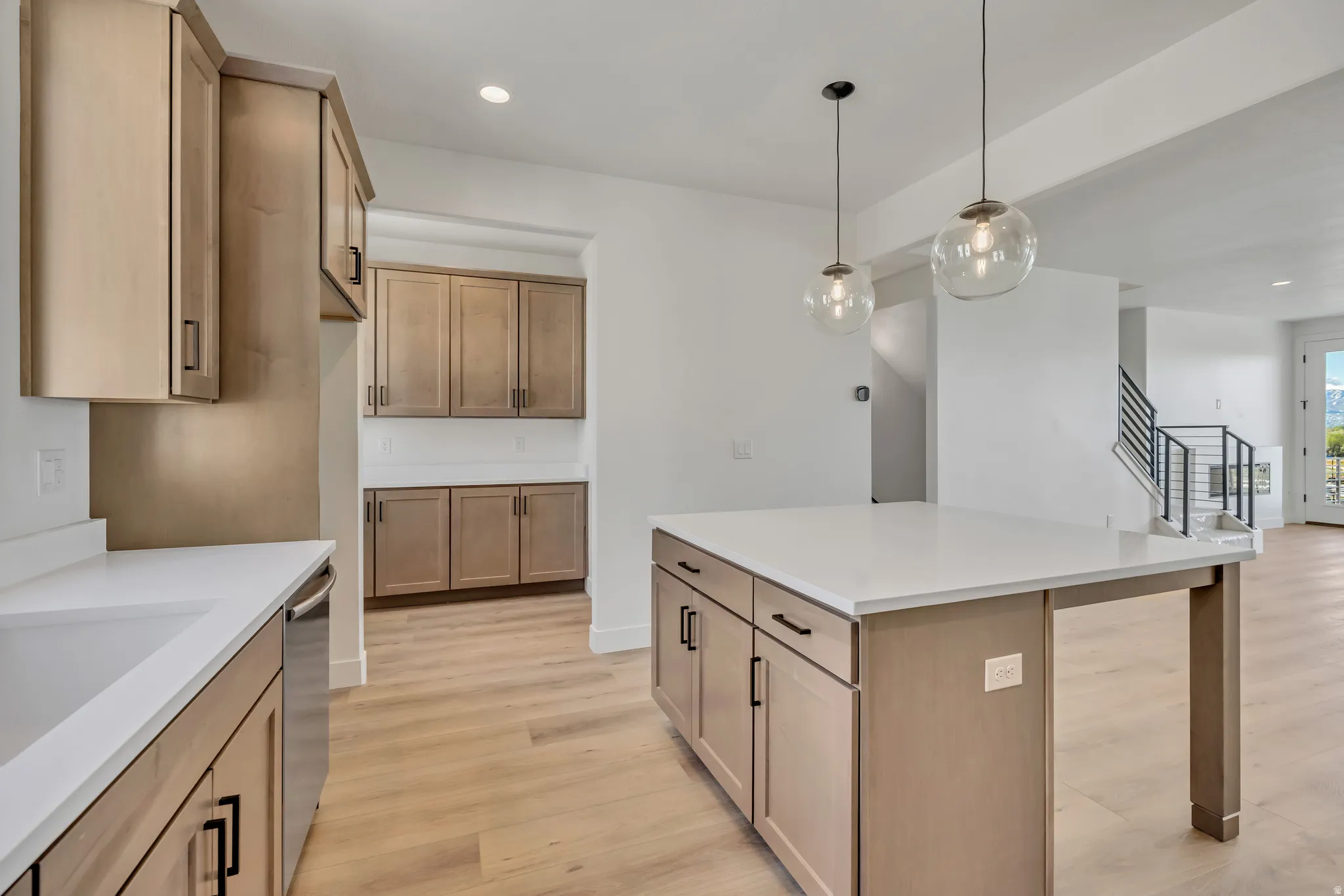 Kitchen featuring light wood-style floors, a kitchen island, stainless steel dishwasher, and wood finish cabinets