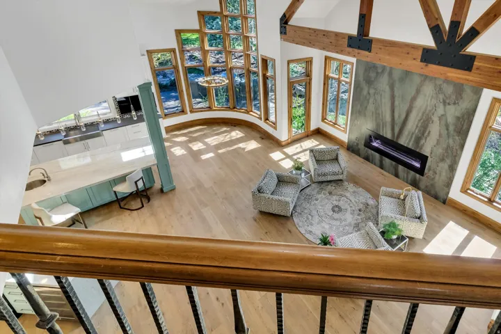 Living room with a tiled fireplace, a high ceiling, and light wood-style flooring