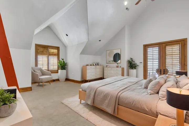 Bedroom featuring light colored carpet, vaulted ceiling, french doors, and ceiling fan. (virtual stanging)