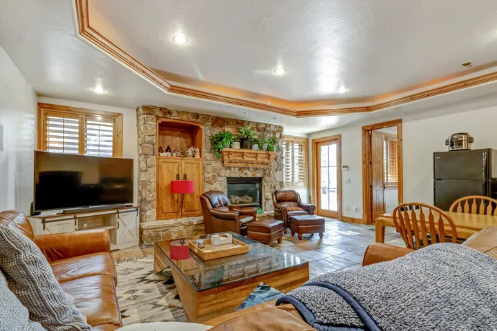 Living area with a raised ceiling and a stone fireplace