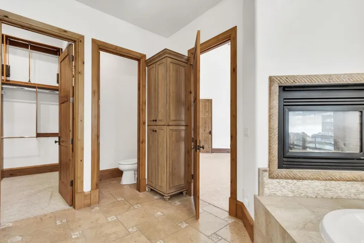 Full bath featuring stone tile floors and a bath and fireplace