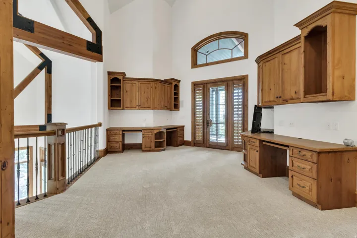 Unfurnished office featuring built in study area, light colored carpet, and a high ceiling