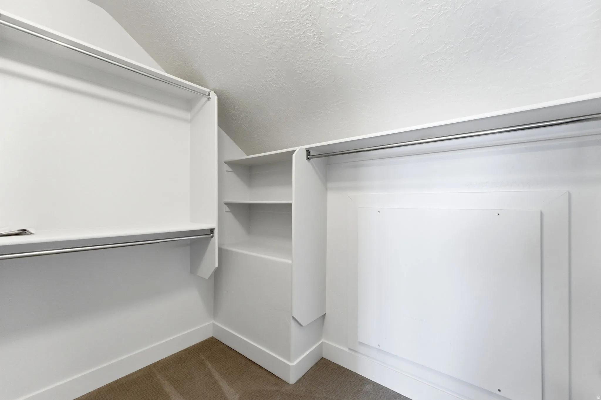 Walk in closet featuring lofted ceiling and dark colored carpet