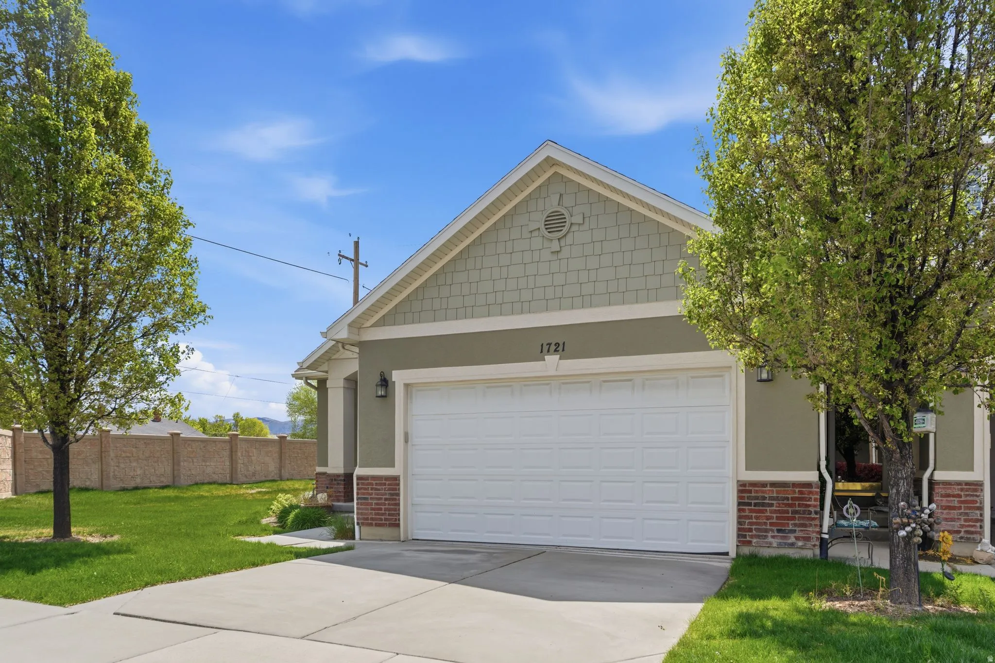 View of front of house featuring a front lawn, driveway, brick siding, an attached garage, and stucco siding