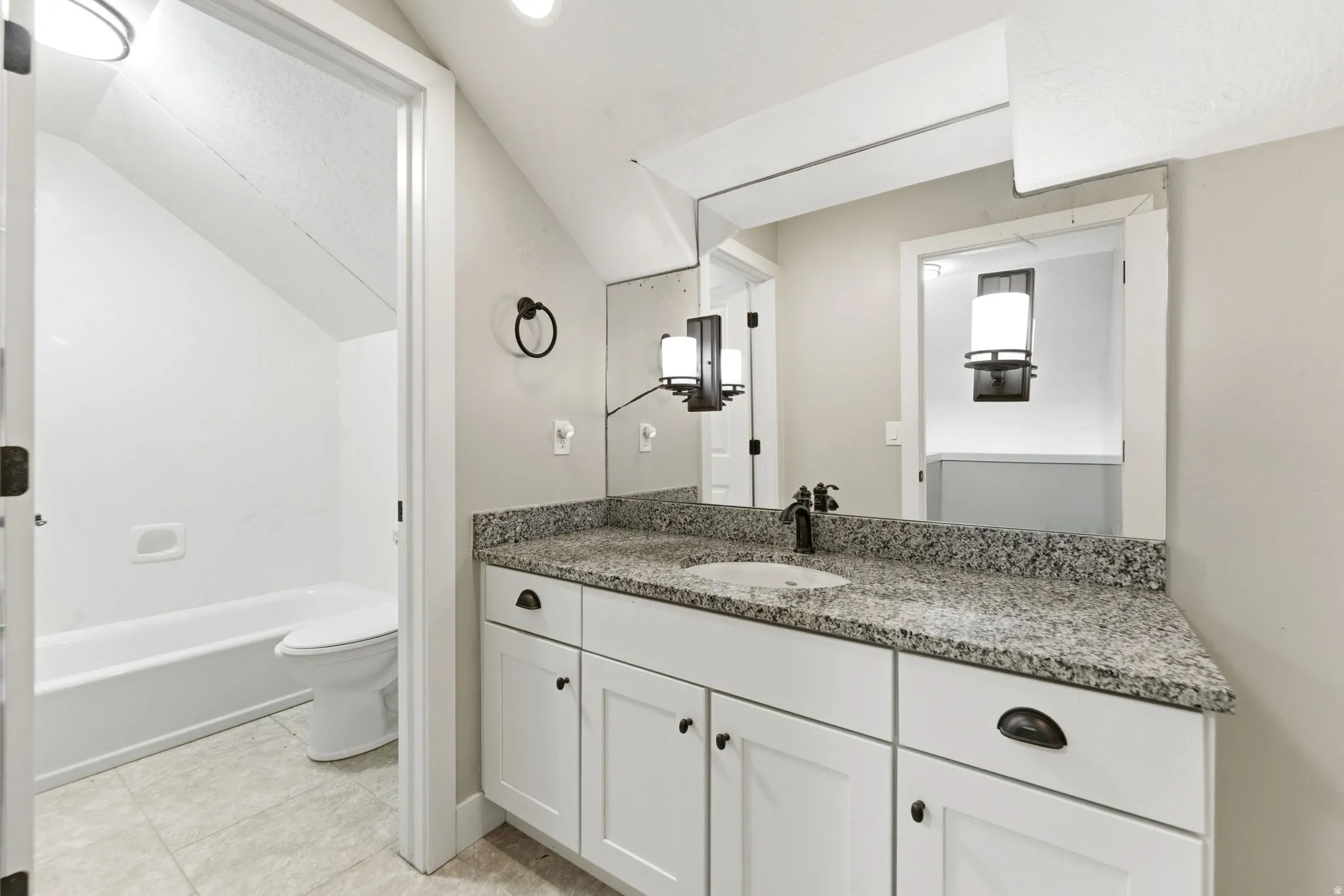 Bathroom featuring vanity, vaulted ceiling, and light tile patterned flooring