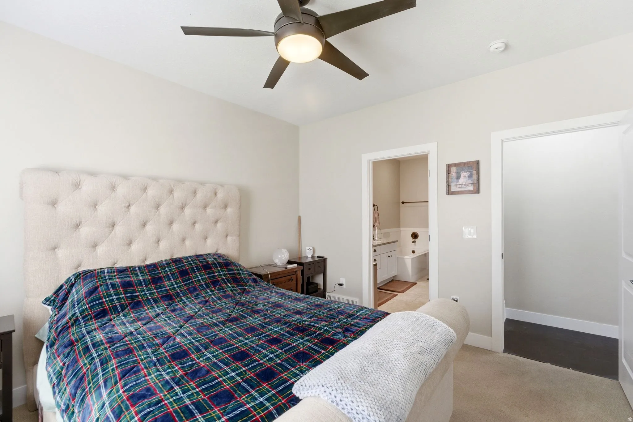 Bedroom featuring ensuite bathroom, light colored carpet, and a ceiling fan