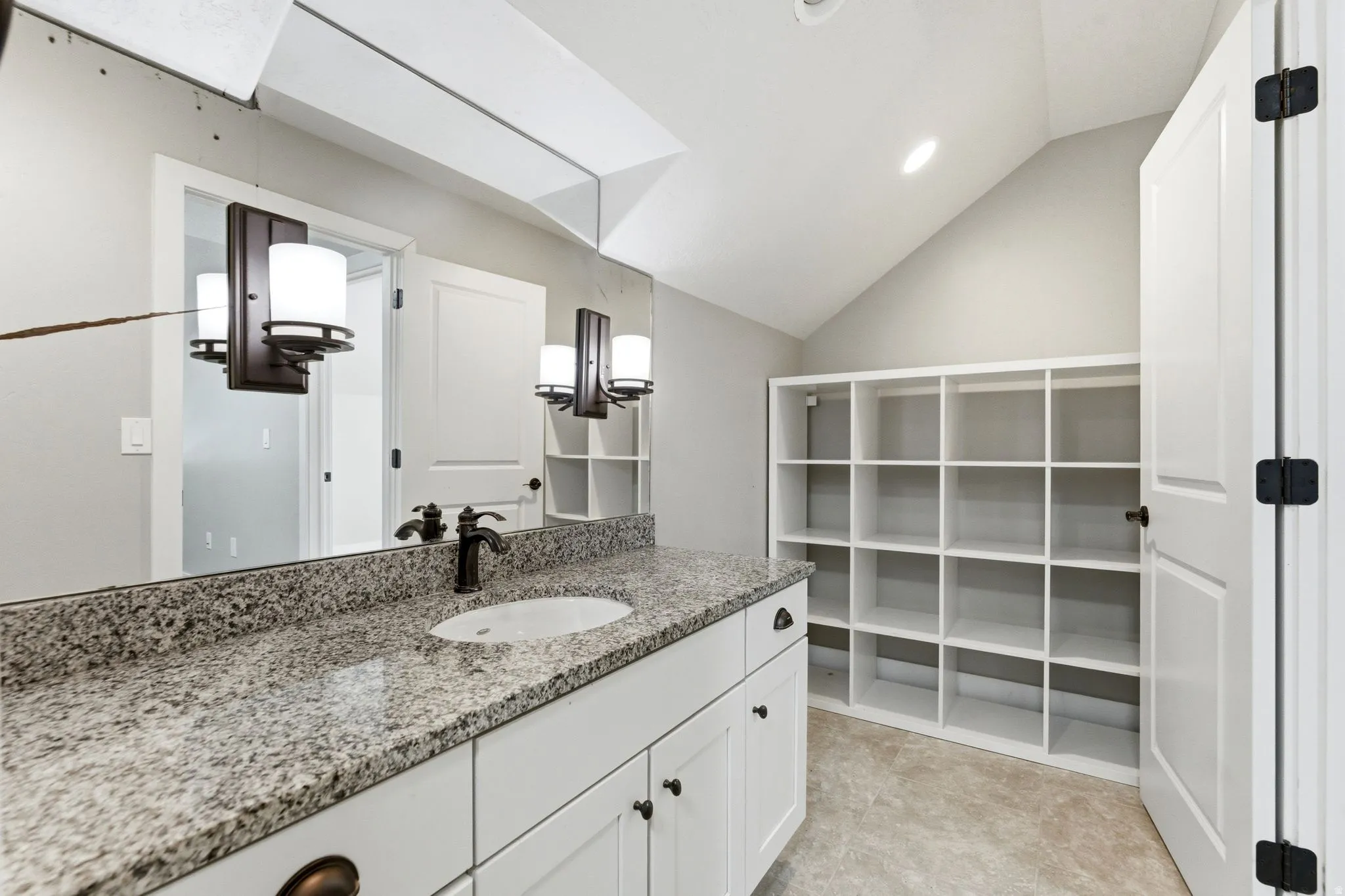Bathroom with vanity, lofted ceiling, and a walk in closet