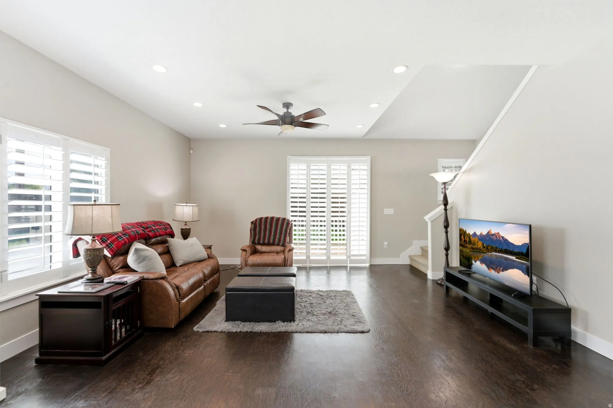 Living room featuring dark wood-type flooring, plenty of natural light, a ceiling fan, and recessed lighting
