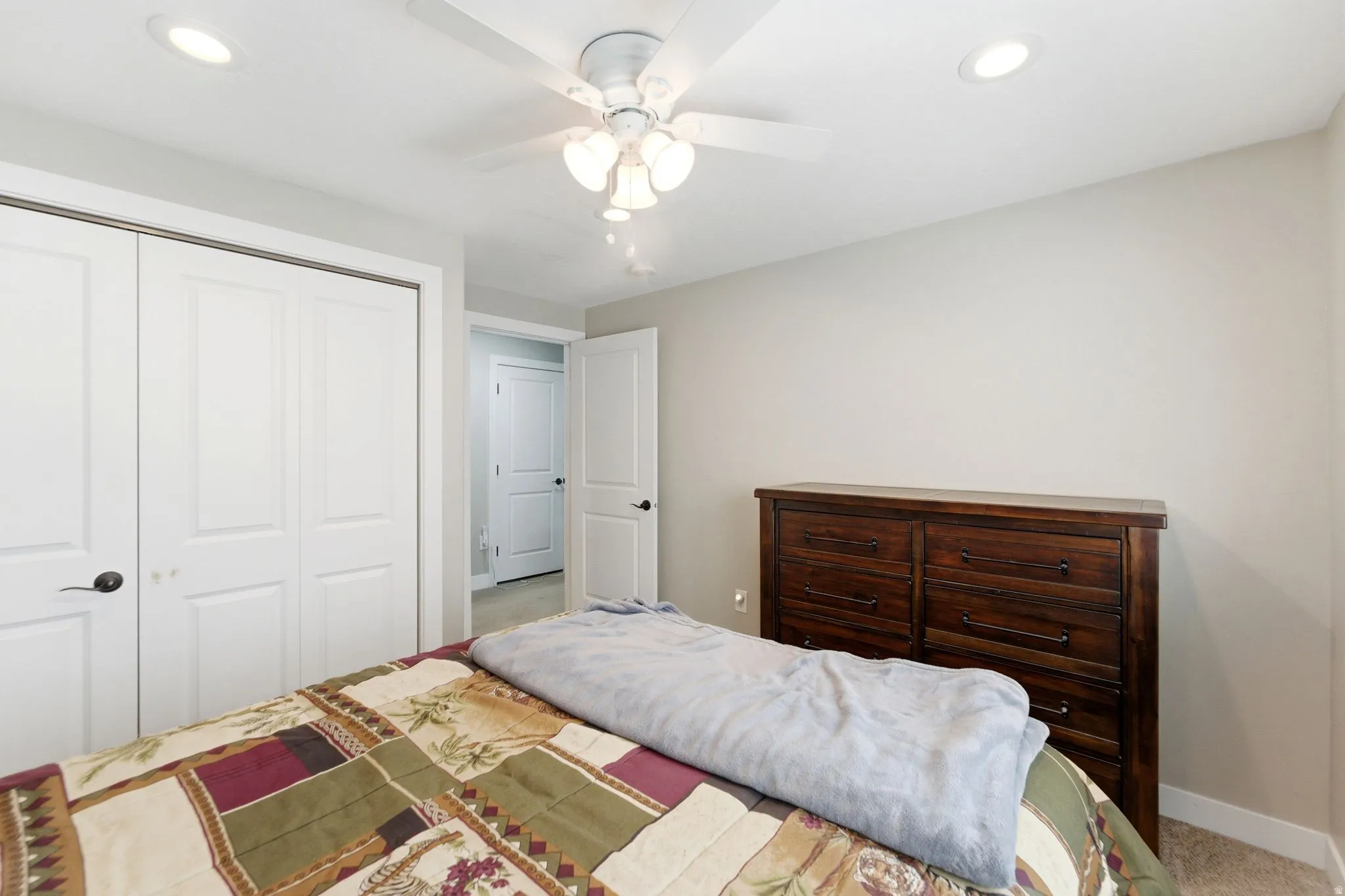 Bedroom with a closet, recessed lighting, ceiling fan, and light carpet