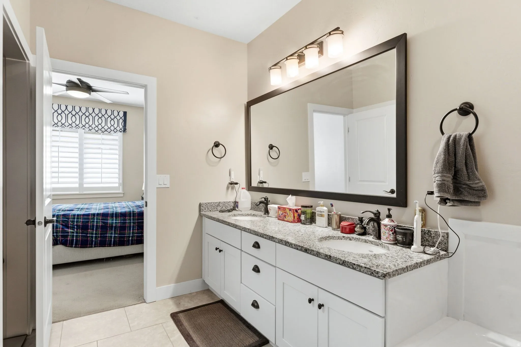 Ensuite bathroom featuring double vanity and light carpet