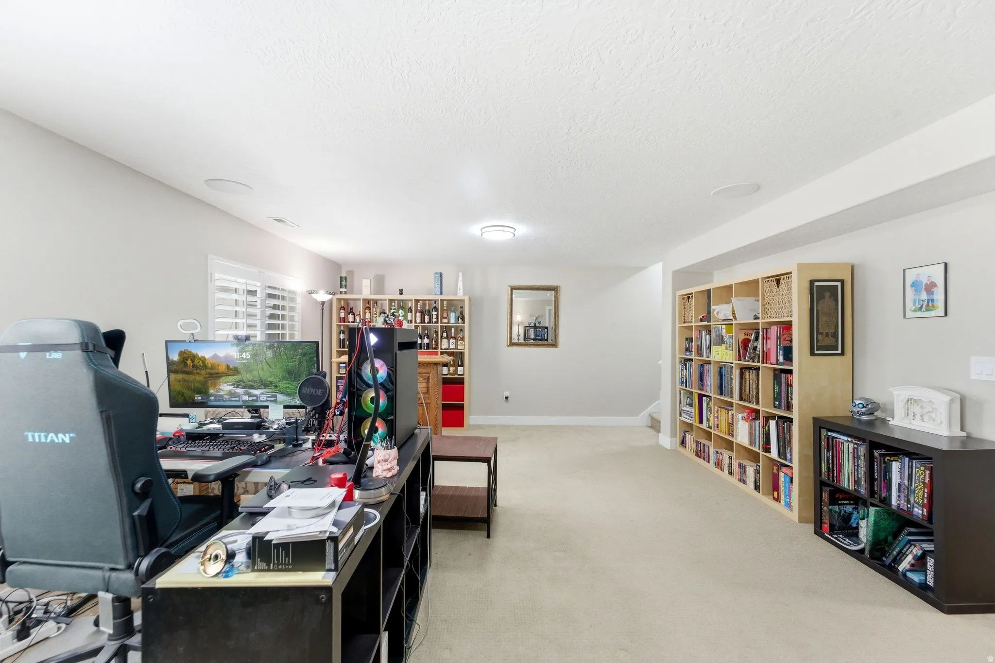Home office with light colored carpet and a textured ceiling