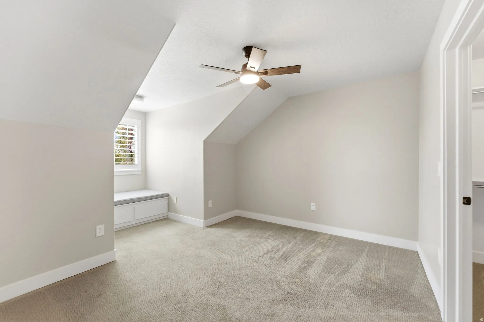 Additional living space featuring vaulted ceiling, light colored carpet, and a ceiling fan