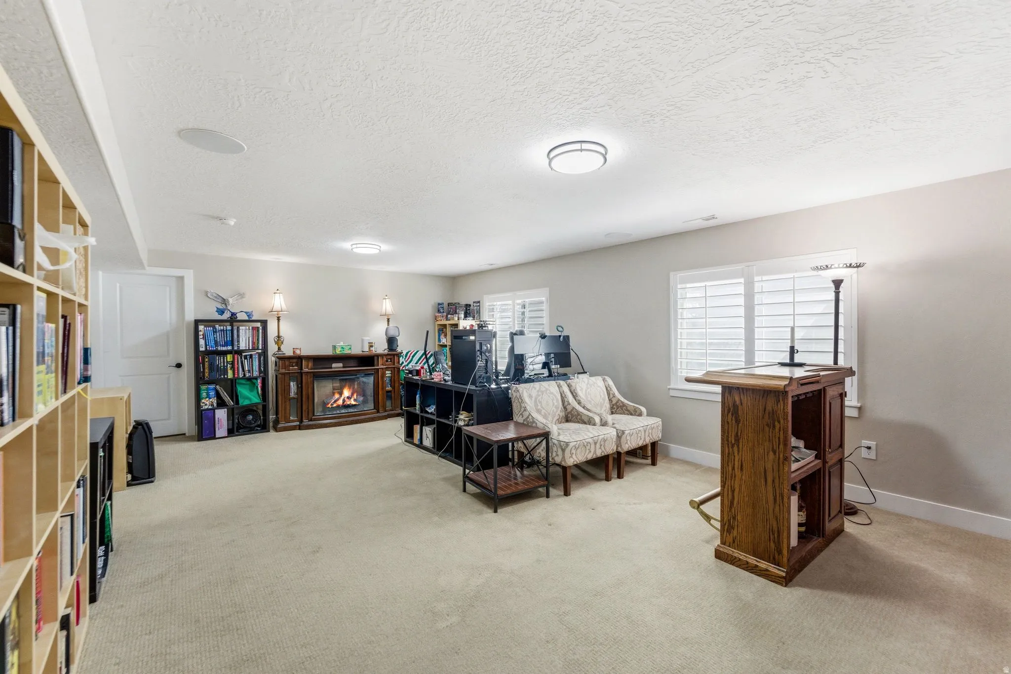 Living area featuring light carpet, a textured ceiling, and a glass covered fireplace