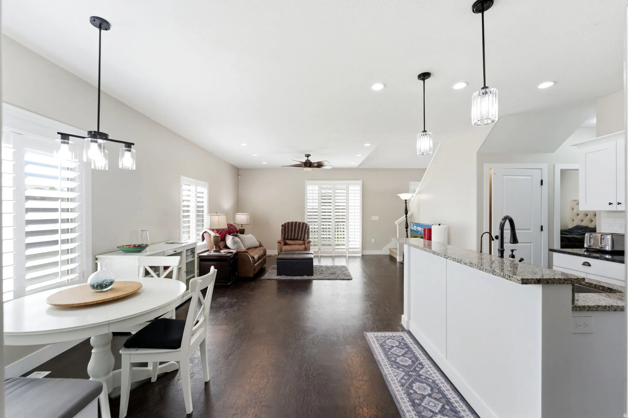 Kitchen featuring white cabinets, dark stone countertops, open floor plan, ceiling fan, and dark wood-style flooring