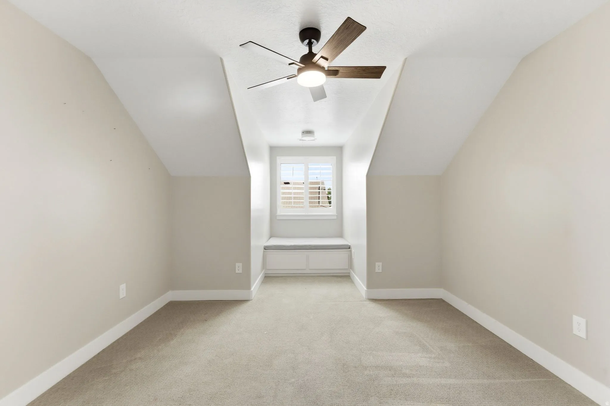 Bonus room with lofted ceiling, light carpet, and ceiling fan