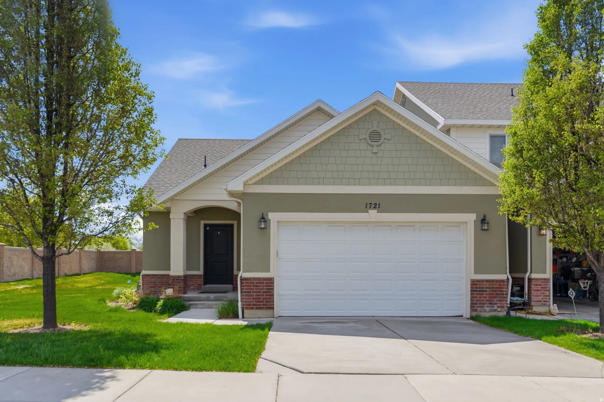 Craftsman inspired home featuring an attached garage, driveway, brick siding, and stucco siding