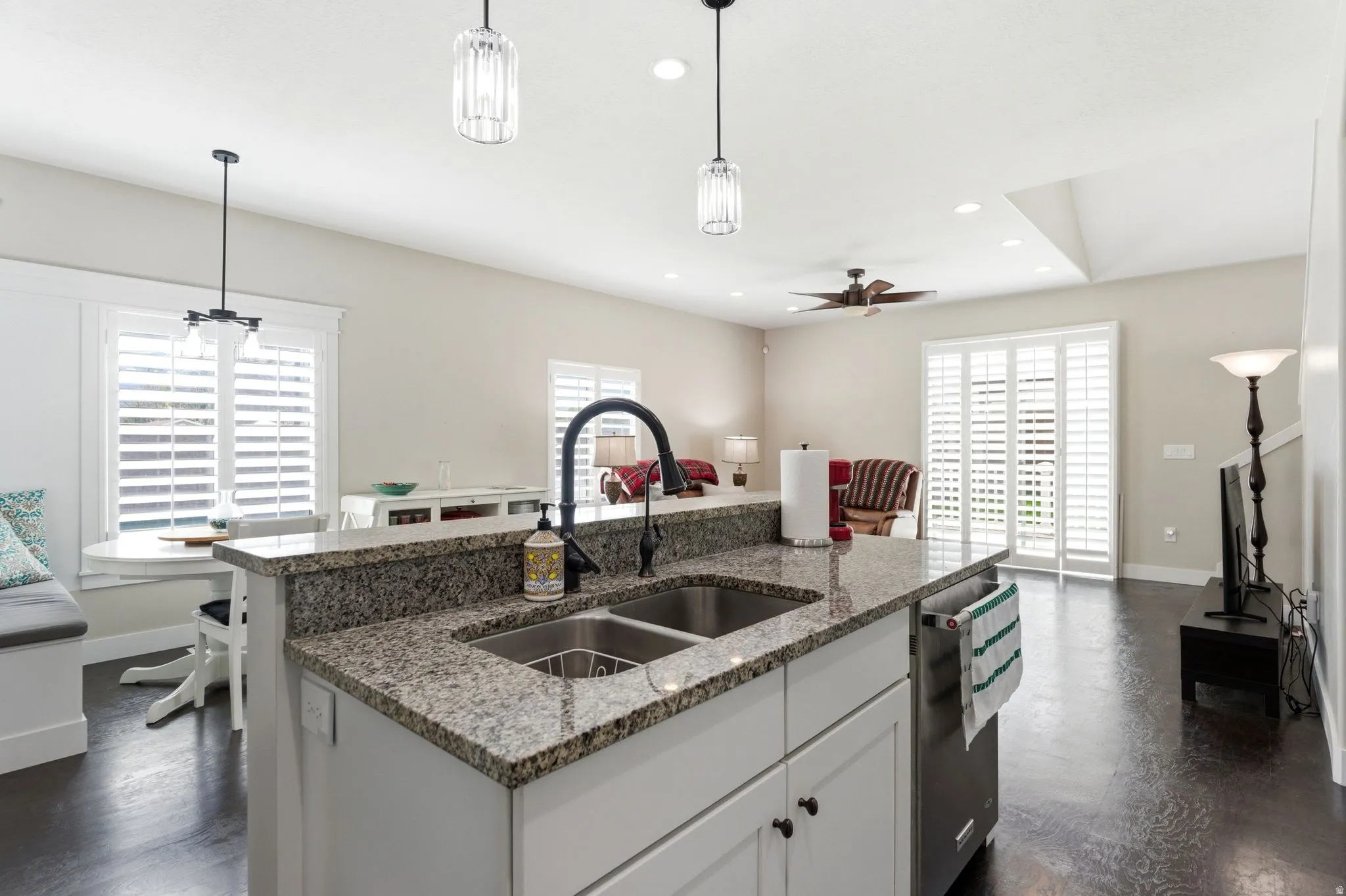 Kitchen featuring white cabinetry, an island with sink, light stone countertops, dark wood-style flooring, and ceiling fan