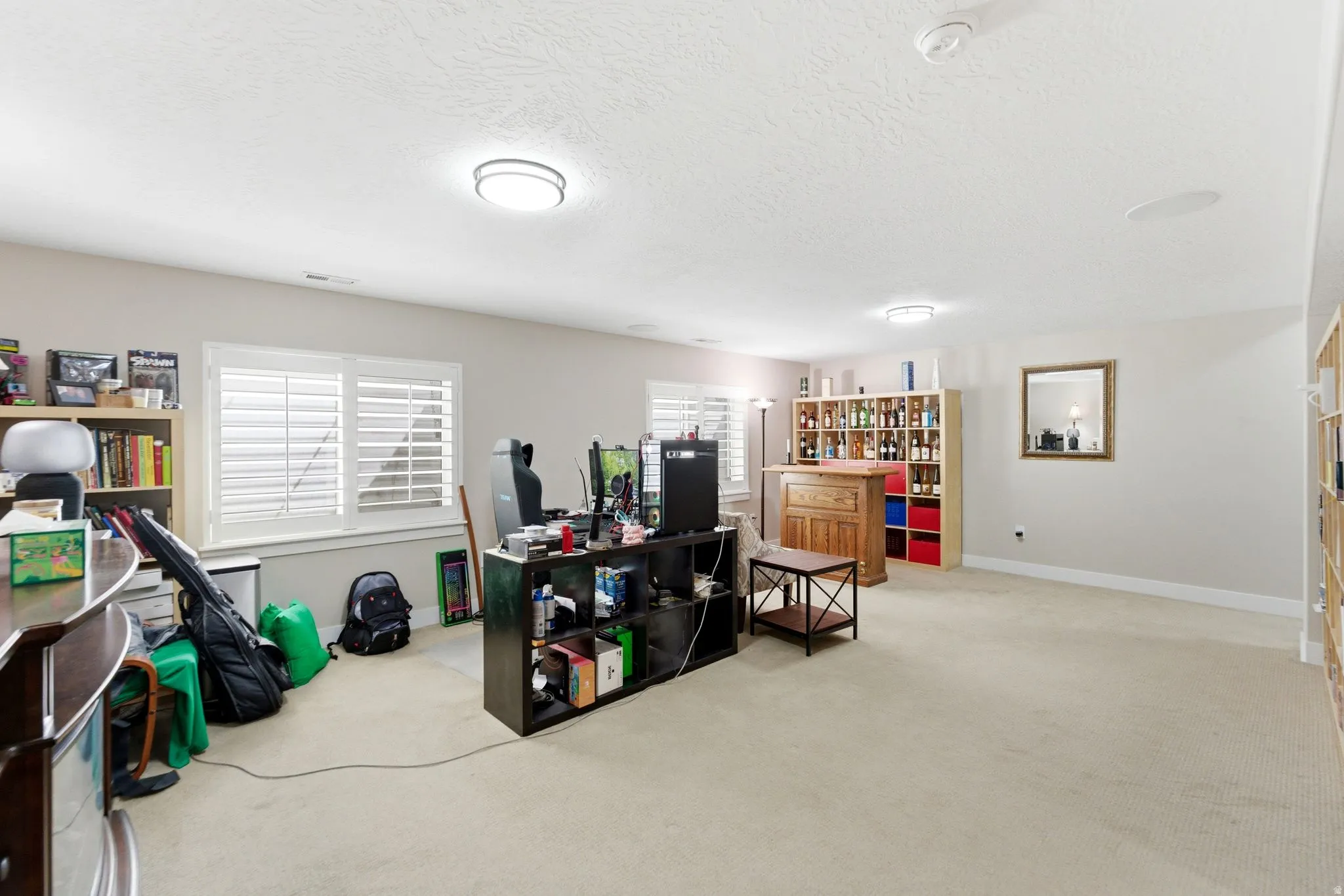 Home office featuring light colored carpet and a textured ceiling