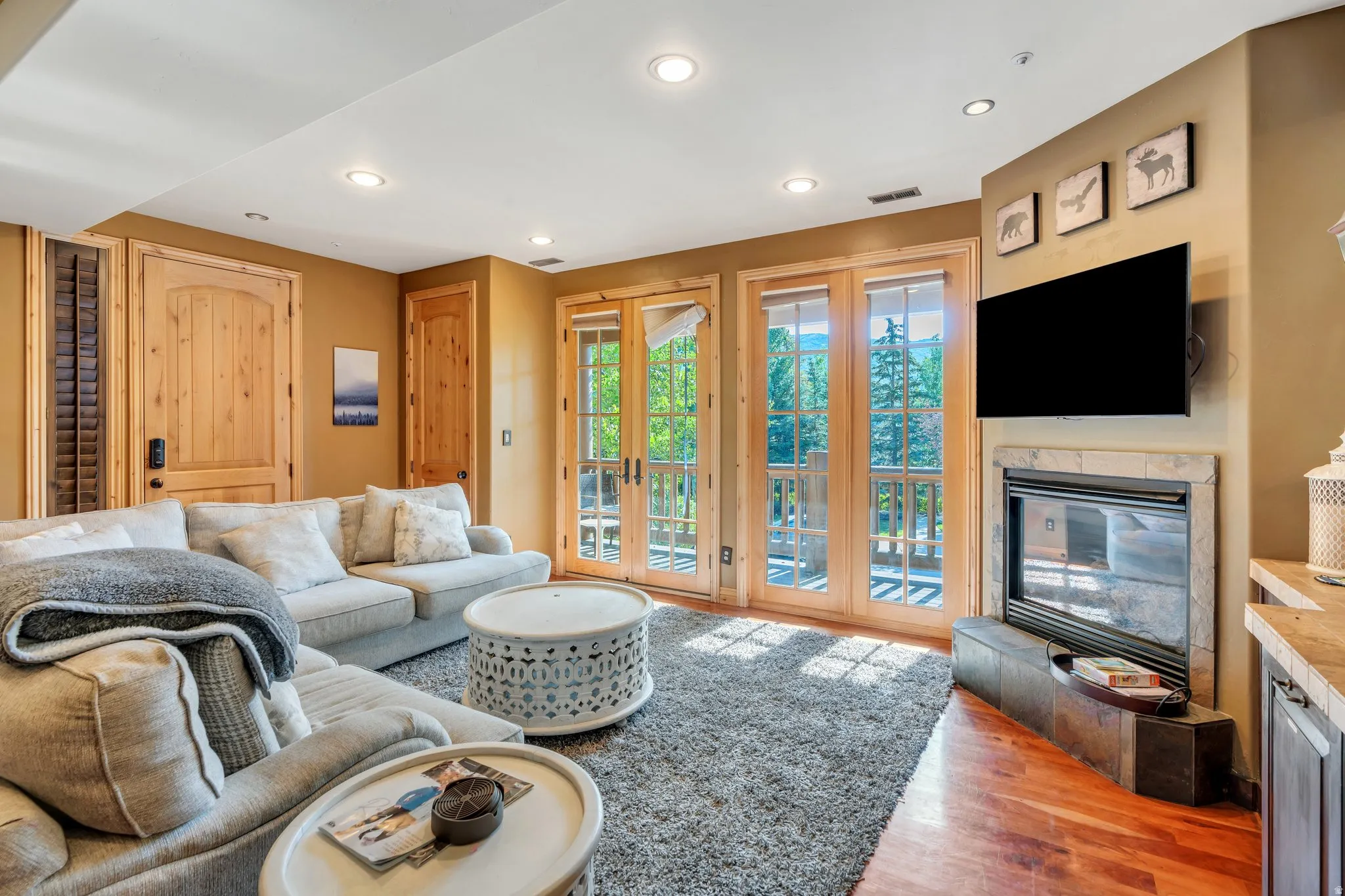 Living area with a glass covered fireplace, light wood-style flooring, recessed lighting, and french doors