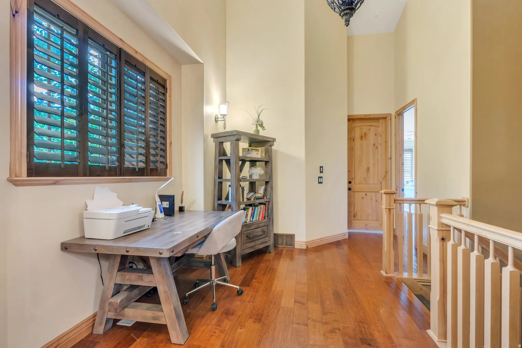 Home office with wood-type flooring, a high ceiling, and healthy amount of natural light