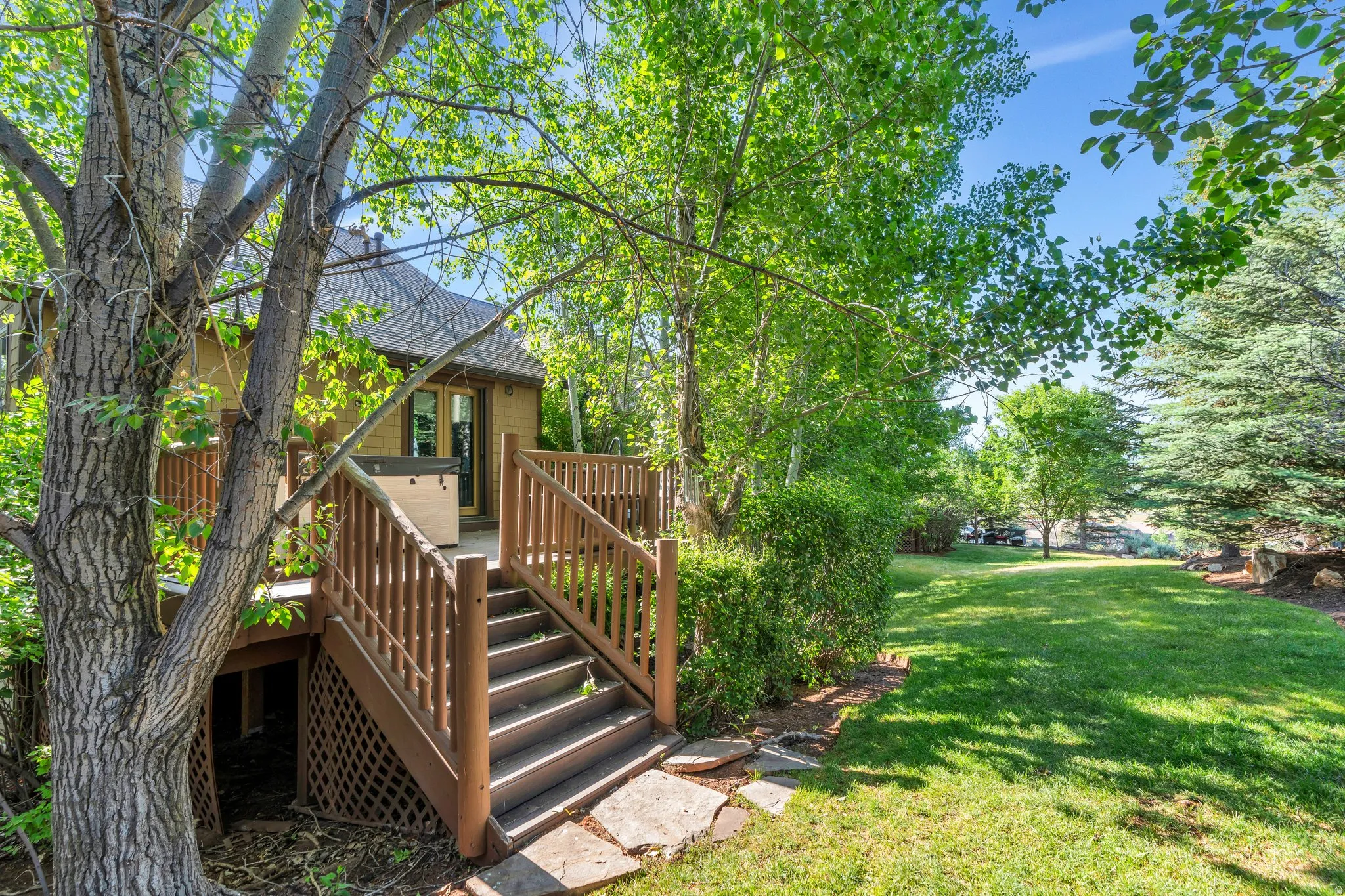 View of grassy yard featuring stairs and a deck