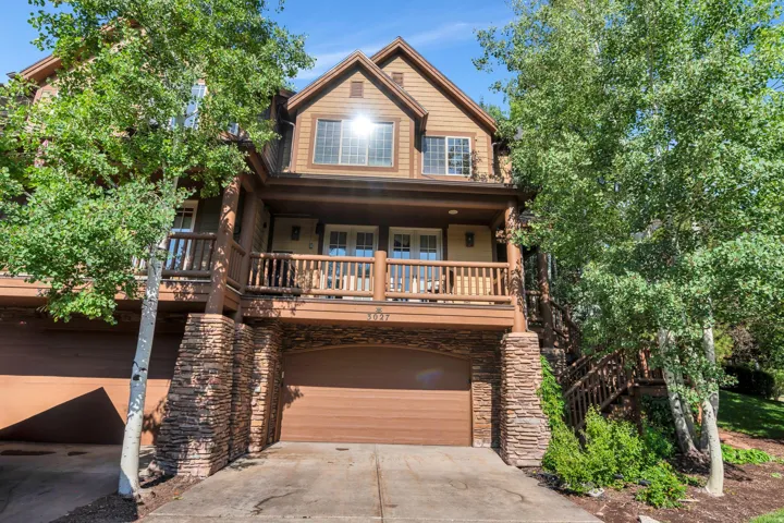 View of front of house featuring concrete driveway, an attached garage, a porch, and stone siding