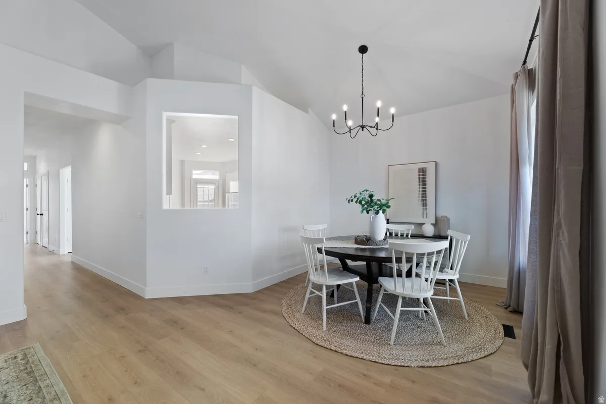 Dining space featuring lofted ceiling, light wood-style floors, and a chandelier