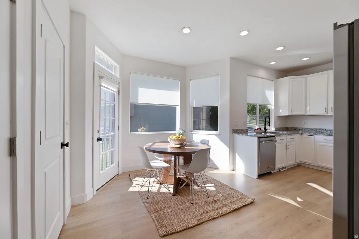 Kitchen featuring white cabinets, dark stone countertops, light wood finished floors, stainless steel appliances, and recessed lighting