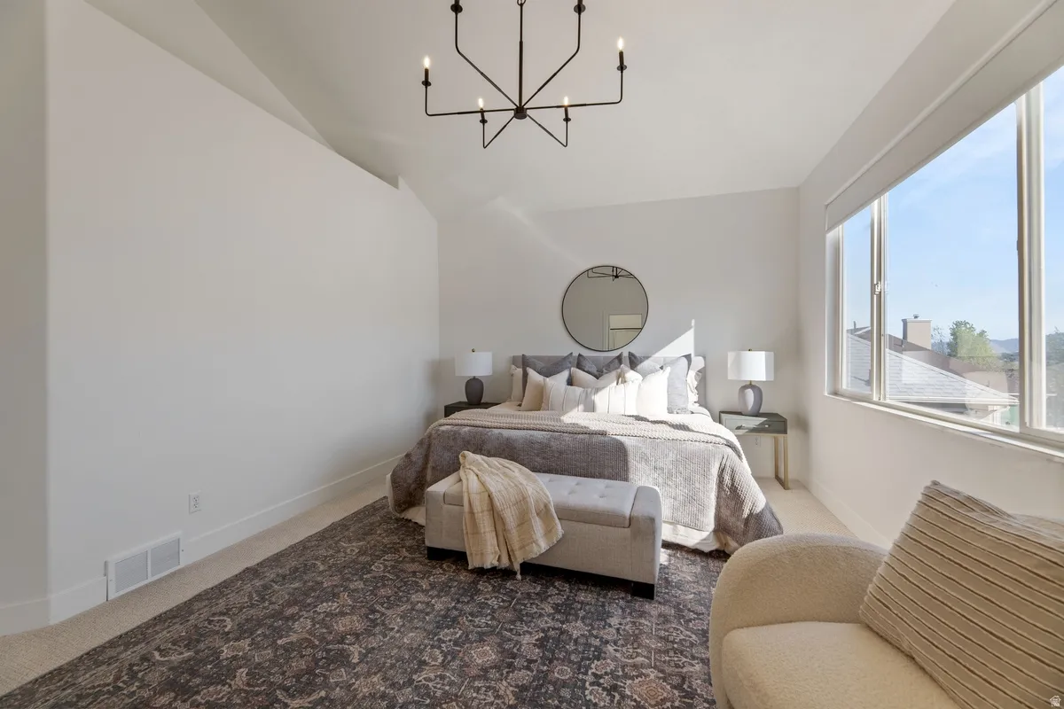 Carpeted bedroom featuring suspended lighting and lofted ceiling