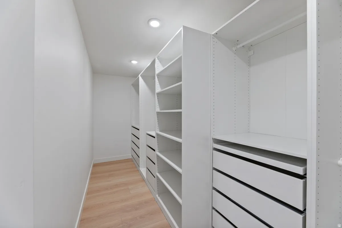 Walk in closet with light wood-style floors