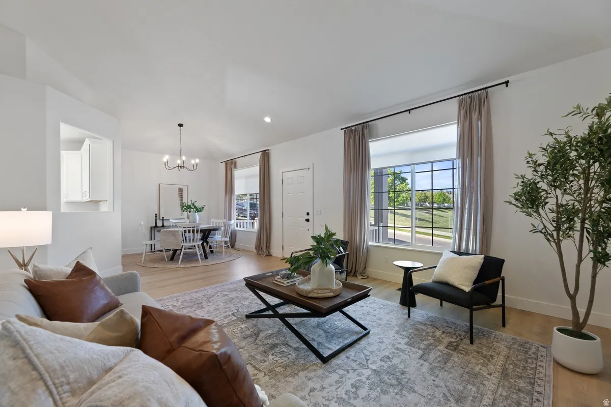 Living room with healthy amount of natural light, light wood-style floors, and suspended lighting