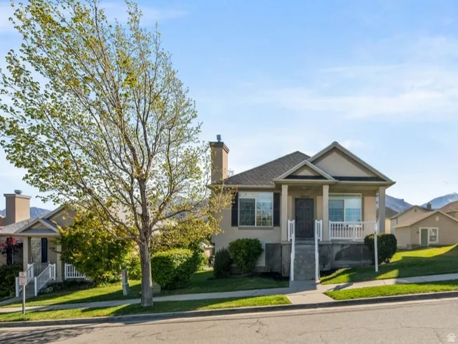 View of front of house with a front lawn, stucco siding, a residential view, and a chimney