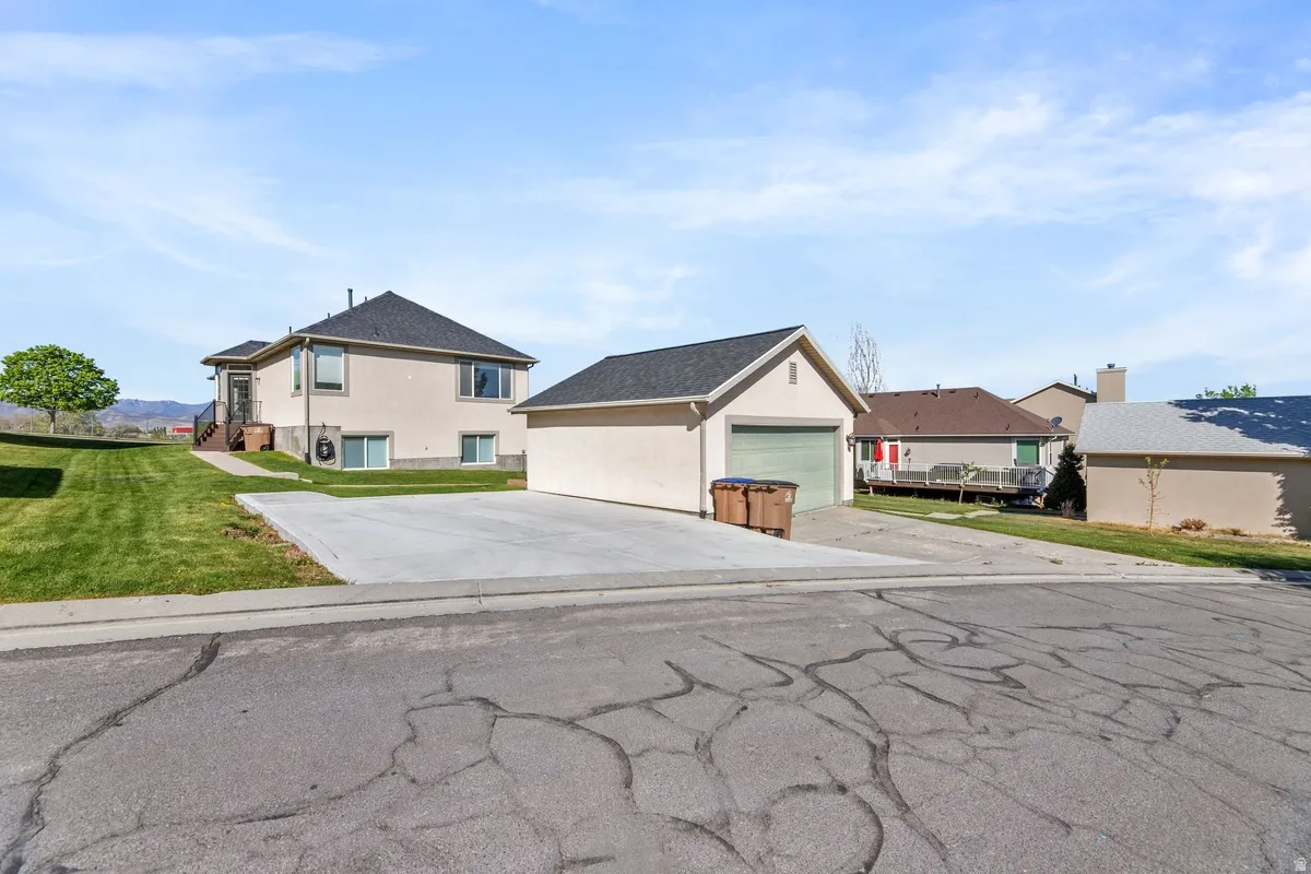 View of front of house featuring an outbuilding, stucco siding, and a front lawn